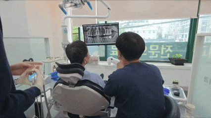 치과 의사가 환자에게 엑스레이 사진을 보여주며 설명하는 모습