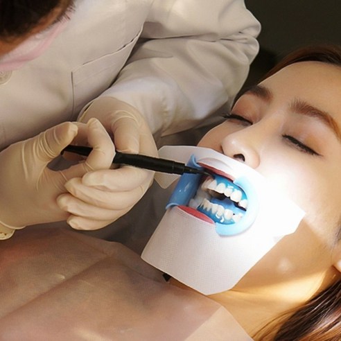 치과에서 환자가 치아 미백 시술을 받는 모습, 의료진이 환자의 치아에 미백제를 도포하고 있다.