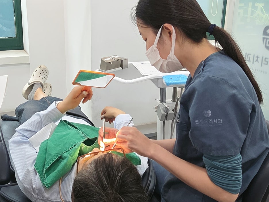 치과 의자에 누워 진료를 받는 환자와 진료 중인 치과 의사의 모습