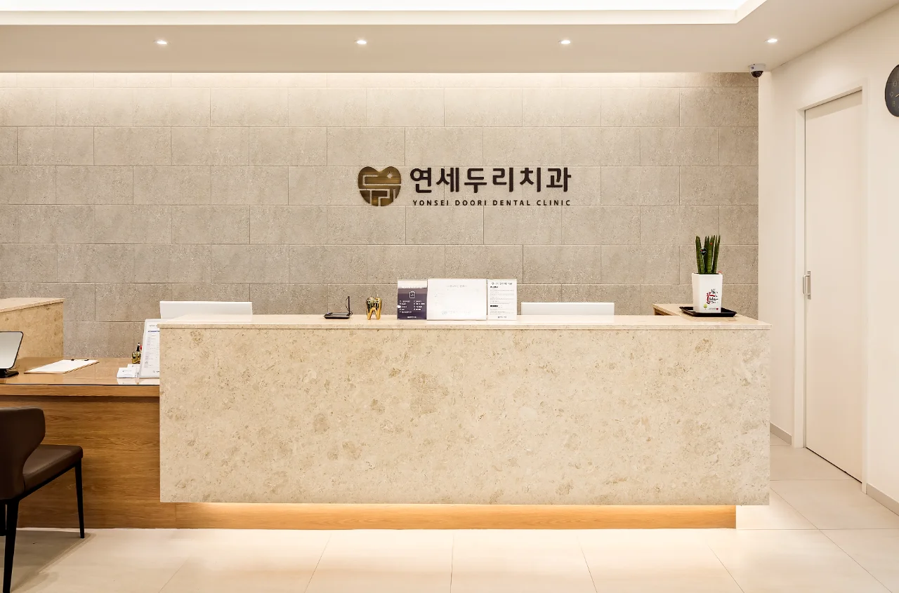 치과 접수대. 연세두리치과 로고가 새겨진 벽면과 대리석 접수대가 보인다.