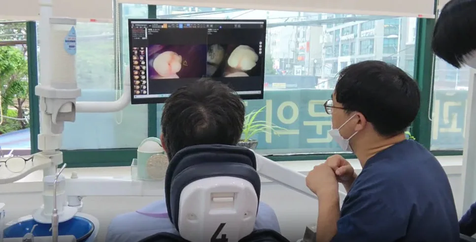 치과 진료실에서 환자가 모니터를 보며 의료진과 상담하는 모습