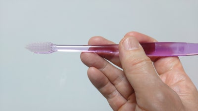 한 손이 핑크색 칫솔을 잡고 있는 측면 사진