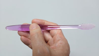 한 손이 핑크색 칫솔을 잡고 있는 측면 사진