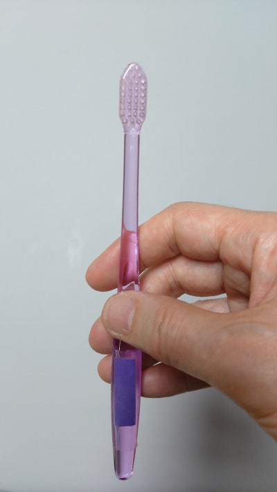 한 손이 핑크색 칫솔을 잡고 있는 정면 사진